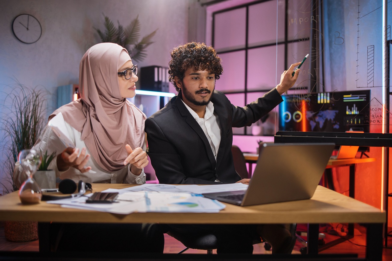 a man and a woman sitting in front of a laptop